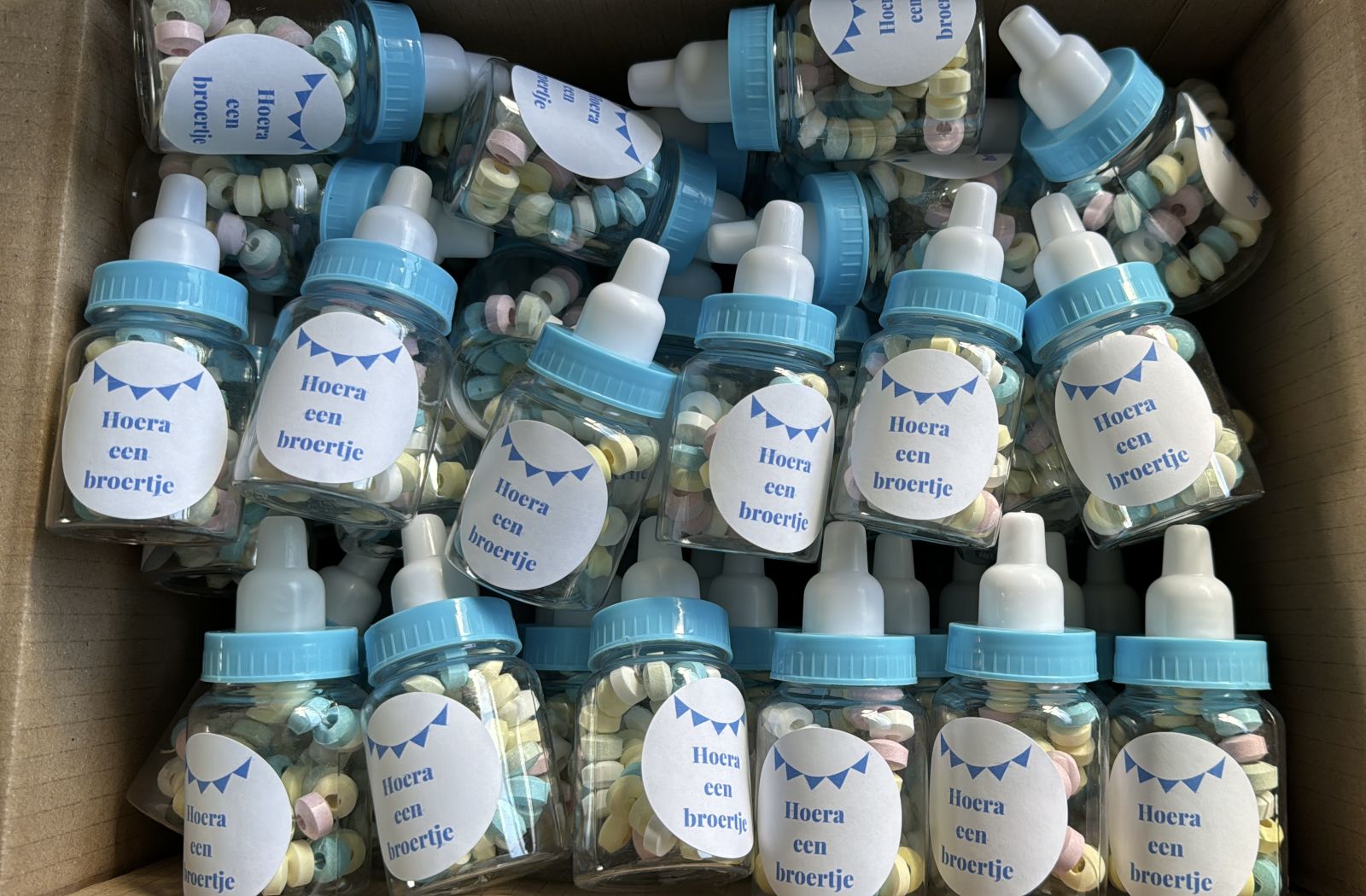 Blauwe babyflesjes met snoep als geboortetraktatie voor een broertje