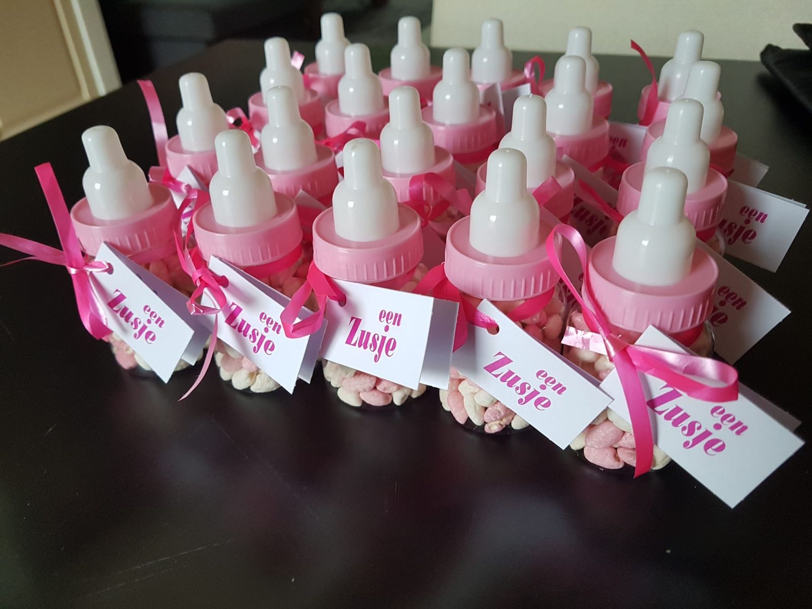 Roze babyflesjes met snoep als geboortetraktatie voor een zusje